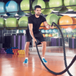 A man uses battle ropes in his gym.