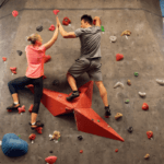 A man and woman exchange a high five while bouldering.