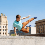 A man does a parkour jump over a cement wall.