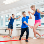 A woman gets help slack lining from a gym instructor.