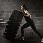 A woman flips a tire in her gym.