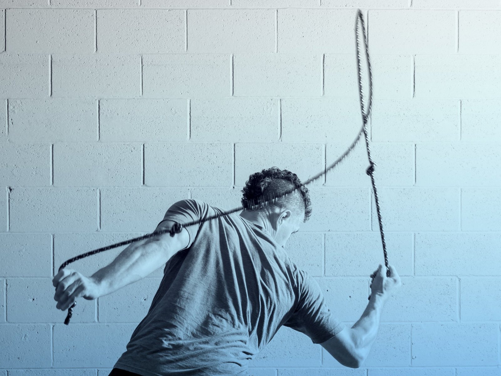 Man seen from behind rotating his torso as a flow rope loops over his shoulder