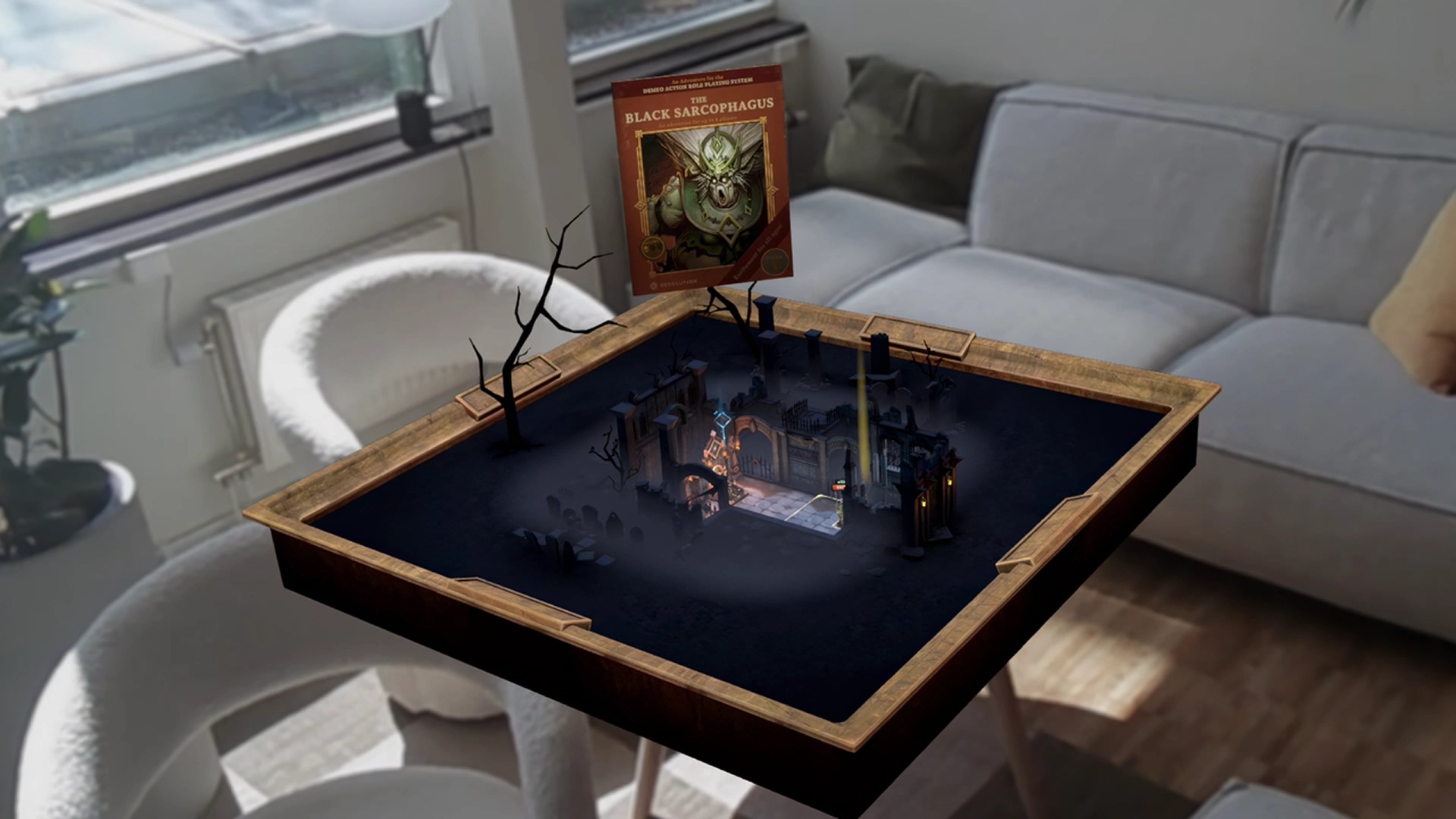 A virtual fantasy tabletop game board with a tiny graveyard and castle appears on top of a real coffee table in a bright living room with a gray sofa